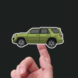 Może przedstawiać: Naklejka zielonego SUV-a, widok z boku samochodu z czarnymi kołami i czarnym dachem. Naklejka znajduje się na palcu.