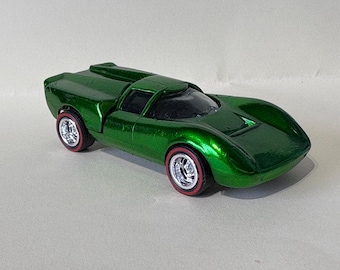 May include: A metallic green toy car with a sleek, aerodynamic design. The miniature vehicle features silver wheels with red-line tires. The toy car is a collectible item, perfect for enthusiasts.