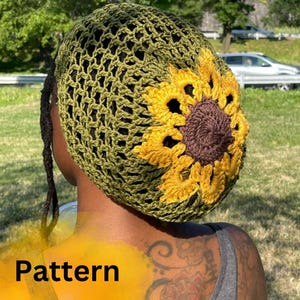 May include: A green crochet hat featuring a sunflower design. The hat is crafted with a mesh pattern and has a brown centre with yellow petals.