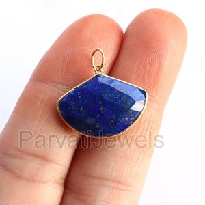 May include: A gold-toned pendant featuring a blue lapis lazuli gemstone with a faceted cut. The pendant is approximately 1 inch in length.