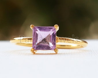 May include: A gold ring with a square-shaped amethyst gemstone. The ring is simple and elegant.