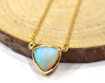 May include: A delicate gold chain necklace with a triangular opal pendant. The opal is a light blue color with hints of pink and white.