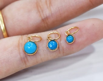 May include: Three small gold-colored pendants with round, bright turquoise stones. Each pendant has a small loop at the top. The pendants are displayed on a light-colored background.