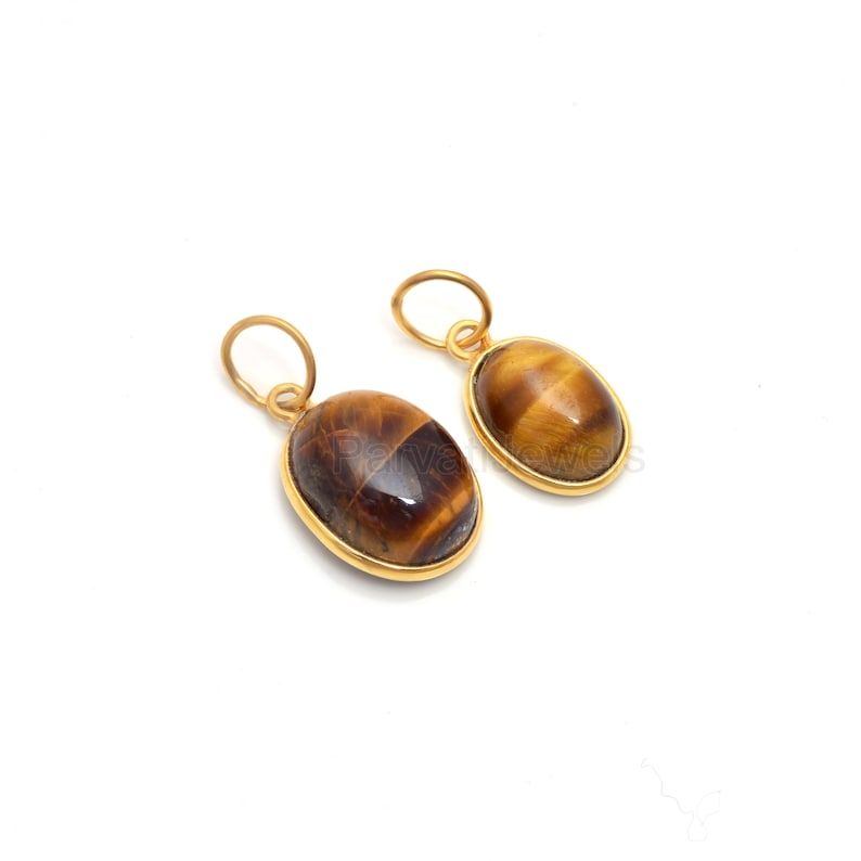 May include: Two gold oval pendants with tiger's eye stones. The stones are a mix of brown and gold.
