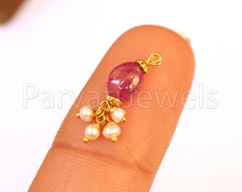 May include: A gold nose ring with a pink gemstone and a cluster of white pearls.