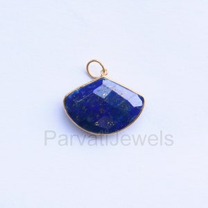 May include: A gold pendant featuring a large, faceted, blue lapis lazuli stone. The stone is set in a gold frame and has a fan shape.