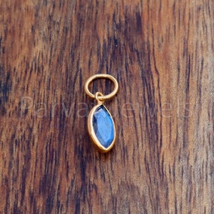 May include: A gold pendant with a blue gemstone in a marquise shape.