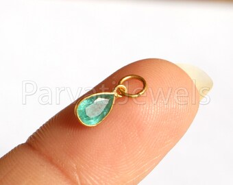 Puede incluir: Un pequeño colgante de oro con una piedra preciosa de esmeralda en forma de lágrima.