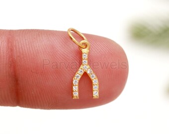 Puede incluir: Encanto de hueso de la suerte de oro con piedras de circonita cúbica transparentes. El encanto es pequeño y delicado, perfecto para agregar un toque de brillo a las joyas.