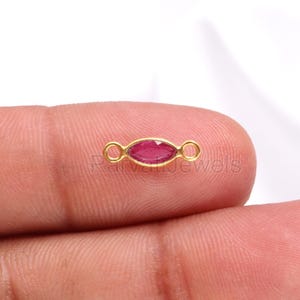 Peut inclure: Connecteur en or avec une pierre précieuse rouge en forme de marquise. Le connecteur a deux boucles de chaque côté.