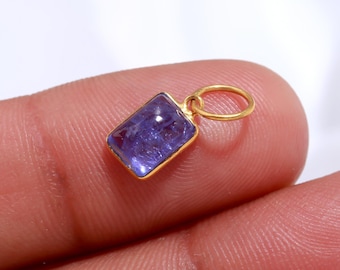 Könnte beinhalten: Ein goldener Anhänger mit einem rechteckigen blauen Edelstein. Der Anhänger hat eine kleine Schlaufe zum Anbringen an einer Kette.