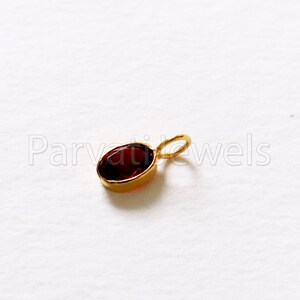 May include: A gold pendant with a red oval gemstone.
