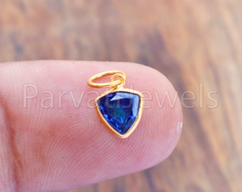 May include: A gold pendant with a blue triangular gemstone. The pendant has a loop for attaching to a chain.