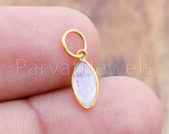 May include: A gold pendant with a white moonstone gemstone in an oval shape. The pendant has a small loop at the top for attaching to a chain.