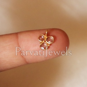 May include: A gold nose ring with three clear gemstones in a flower shape.