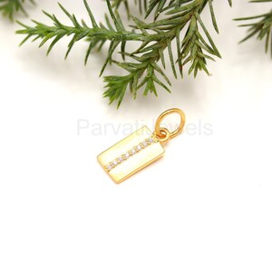 Puede incluir: Pendiente de oro con forma rectangular y una fila de peque&ntilde;as piedras transparentes.
