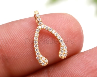 Puede incluir: Encanto de hueso de la suerte de tono dorado con piedras de circonita cúbica transparentes.