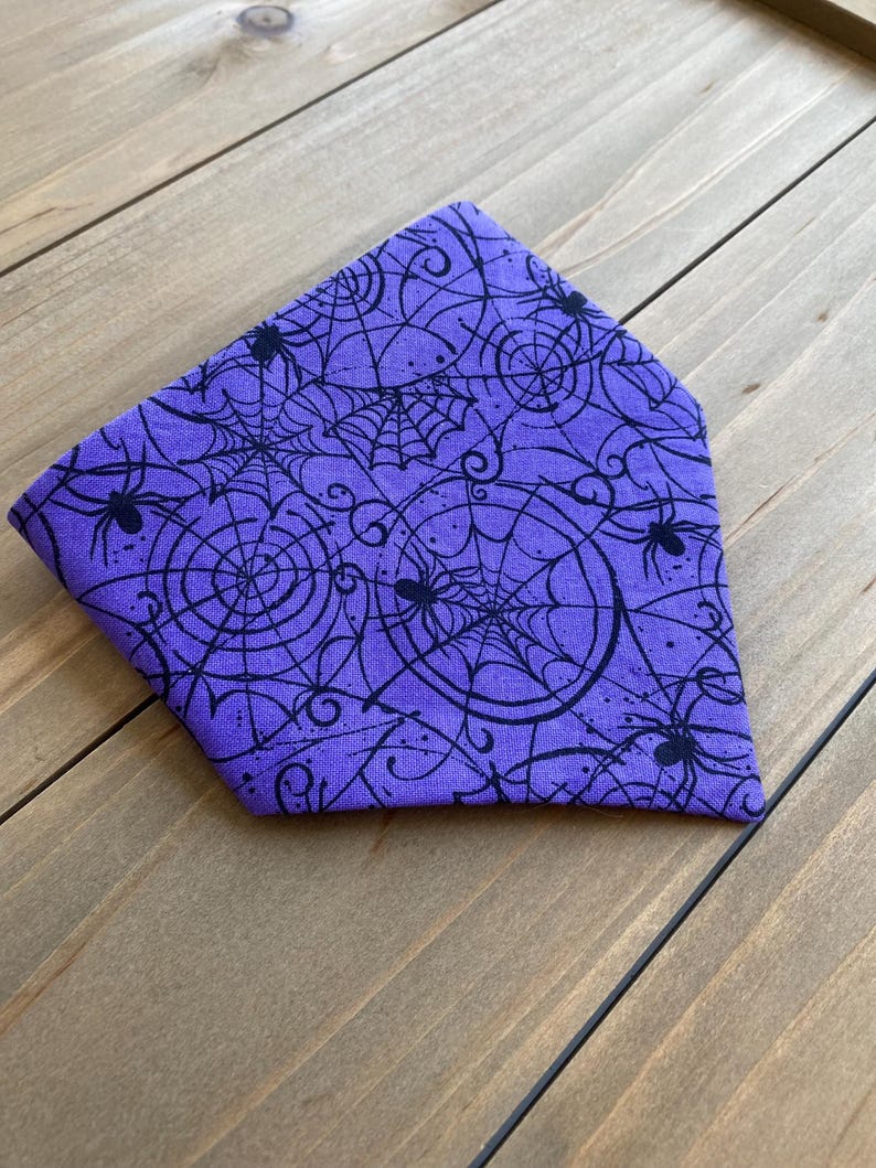 K&ouml;nnte beinhalten: Lilafarbener Bandana mit einem schwarzen Spinnennetz- und Spinnenmuster.
