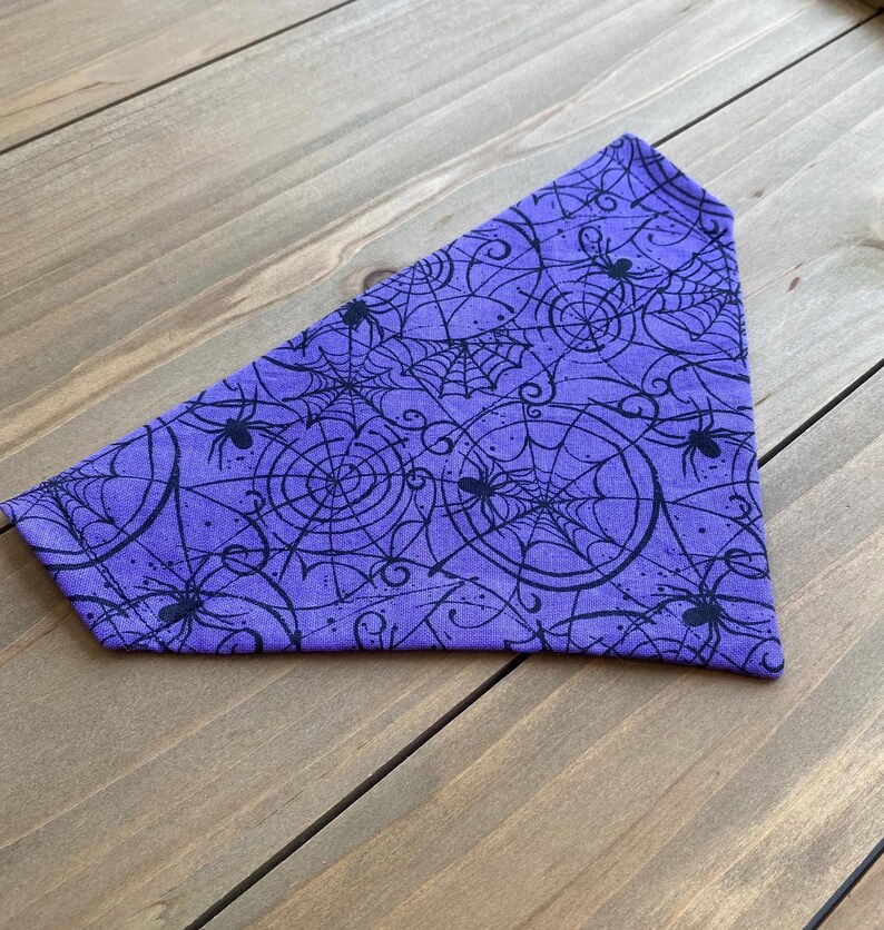 K&ouml;nnte beinhalten: Lilafarbener Bandana mit einem schwarzen Spinnennetz- und Spinnenmuster.