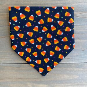 May include: Black bandana with a pattern of orange and white candy corn and colorful sprinkles.