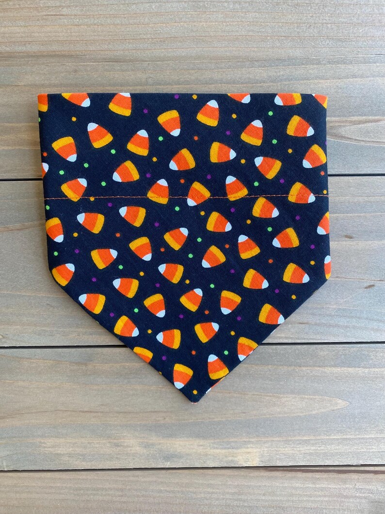 May include: Black bandana with a pattern of orange and white candy corn and colorful sprinkles.