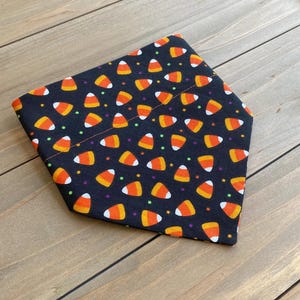 May include: Black bandana with a pattern of orange and white candy corn and colorful sprinkles.