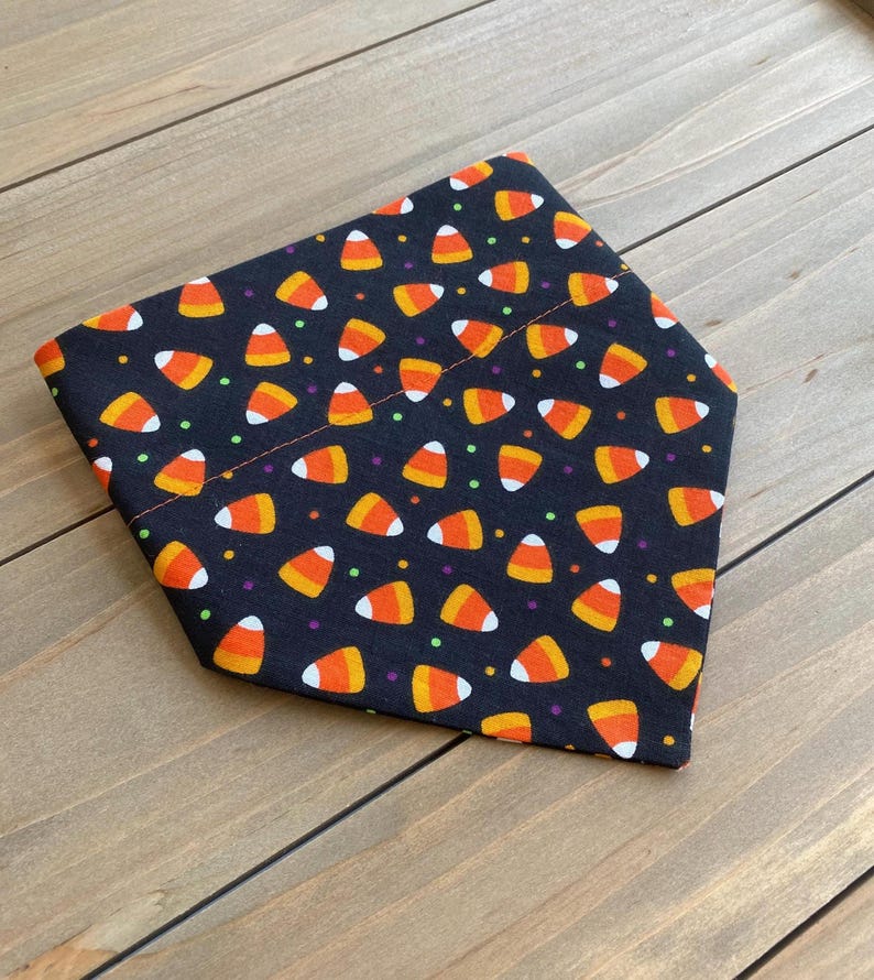 May include: Black bandana with a pattern of orange and white candy corn and colorful sprinkles.