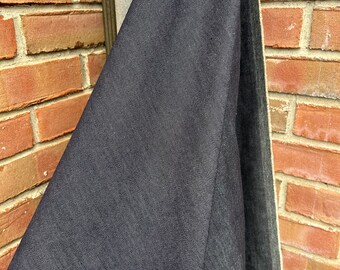May include: Close-up of a dark gray fabric with a subtle texture. The fabric is folded over itself, revealing a lighter gray fabric underneath.