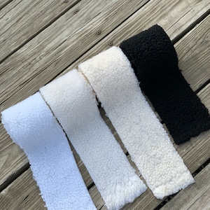 May include: Four rolls of white and black faux fur fabric. The fabric is soft and fluffy, and it would be perfect for making blankets, cushions, or other home decor items.