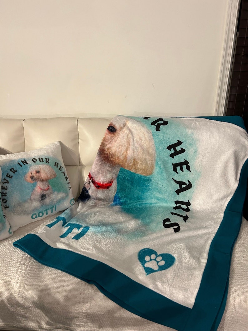 May include: A white plush blanket and pillow set featuring a dog portrait. The blanket has a teal border and the words "FOREVER IN OUR HEARTS" and "GOTTI". The pillow has the same dog portrait and the words "FOREVER IN OUR HEARTS" and "GOTTI".