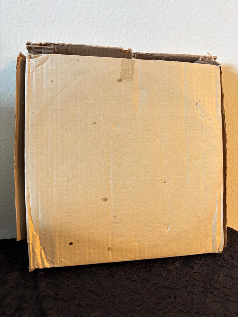Peut inclure: Une bo&icirc;te en carton rectangulaire partiellement ouverte. La bo&icirc;te est en carton ondul&eacute; et de couleur brun clair. Les bords de la bo&icirc;te sont l&eacute;g&egrave;rement us&eacute;s et il y a du ruban adh&eacute;sif sur le dessus.