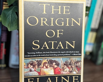 Peut inclure: Un livre de poche intitulé The Origin of Satan par Elaine Pagels. La couverture noire présente un texte doré et une peinture historique représentant une foule. Une citation du Boston Globe est imprimée sous le titre, et le nom de l'auteur est en bas.