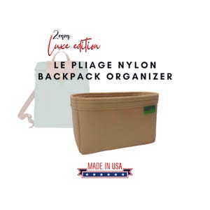 Pode incluir: Organizador de mochila Le Pliage Nylon em feltro bege com o texto "2mm Luxe edition" e "MADE IN USA" com cinco estrelas.