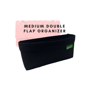 Op de afbeelding: Zwarte vilten tassenorganizer met een groen label, voor een roze gewatteerde handtas. De tekst "MEDIUM DOUBLE FLAP ORGANIZER" staat erboven. De organizer is ontworpen om in een handtas te passen.