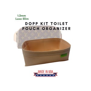 Puede incluir: Un organizador de neceser Dopp Kit beige con interior marrón claro. La imagen también muestra un neceser a juego en el fondo. El texto "1.2mm Luxe Slim" y "Made in USA" son visibles.