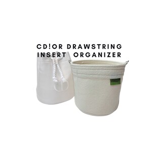 May include: White drawstring bag organizer with a white rope drawstring and a green label that says "GREENING".