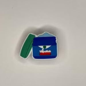 May include: A blue and white VapoRub ointment jar with a green lid. The jar is open and the ointment is visible inside.