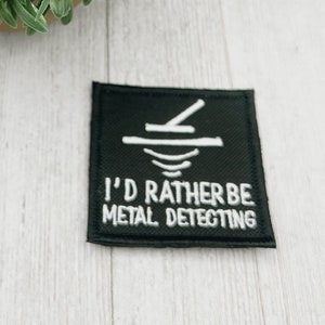 Peut inclure: Patch brodé noir et blanc avec une icône de détecteur de métaux et le texte "I'd rather be metal detecting".