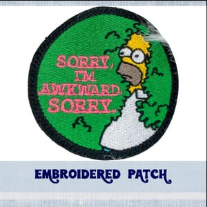 May include: Embroidered patch featuring a yellow cartoon character with the text "Sorry, I'm awkward, Sorry" in pink lettering on a green background.