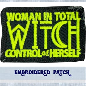 Op de afbeelding: Zwarte geborduurde patch met gele stiksels. De patch heeft de tekst "Woman in total control of herself Witch".