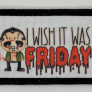 Puede incluir: Un parche blanco con borde negro presenta un personaje de dibujos animados con una máscara de hockey y sosteniendo un cuchillo ensangrentado. El texto "I wish it was FRIDAY" está escrito en letras rojas que gotean.