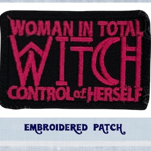 May include: Embroidered patch with black fabric and pink stitching. The text reads "Woman in total control of herself" with the word "Witch" in large letters.