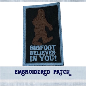 May include: Embroidered patch with a brown Bigfoot walking and the text "BIGFOOT BELIEVES IN YOU!" in blue lettering on a black background.