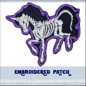 May include: Purple embroidered patch of a skeleton unicorn. The unicorn is white with a black outline and purple details. The patch says "Embroidered Patch" at the bottom.