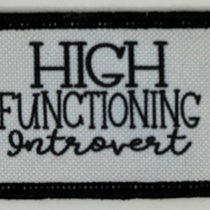Könnte beinhalten: Schwarz-weiß gestickter Aufnäher mit weißem Hintergrund und schwarzem Text, der "HIGH FUNCTIONING Introvert" lautet.