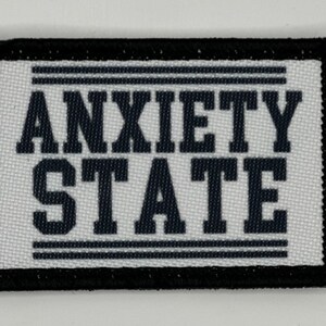 Puede incluir: Parche de tela blanco con borde negro y texto negro que dice "ANXIETY STATE".