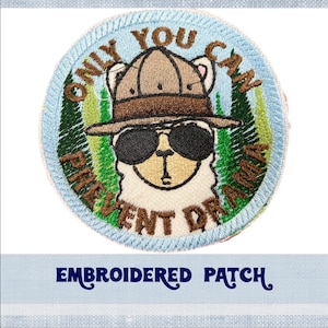 May include: Embroidered patch with a llama wearing sunglasses and a ranger hat. The patch is blue with green trees and the text "Only You Can Prevent Drama".
