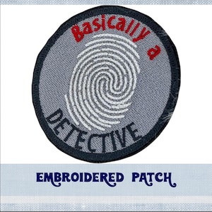 Pode incluir: Etiqueta bordada com fundo cinza e uma impressão digital branca no centro. O texto "Basically a Detective" é bordado em vermelho e preto ao redor da impressão digital.