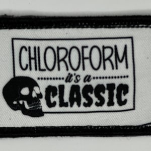May include: A rectangular patch with a black border and the words "CHLOROFORM it's a CLASSIC" in black text. A black skull graphic is on the left. The patch is white with a black border.