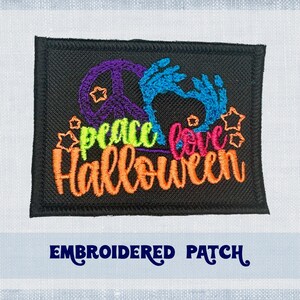 Może przedstawiać: Naszywka haftowana z symbolem pokoju, dłonią ducha i tekstem "Peace Love Halloween" w kolorach tęczy na czarnym tle.